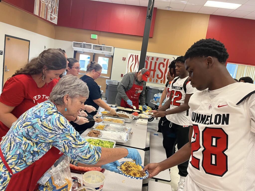 Tiger Chow Volunteer makes a plate for a football player